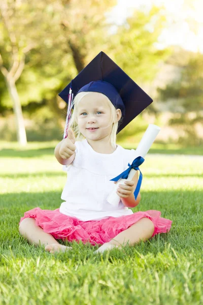 Little Girl In Grass Wearing Graduation Cap Holding Diploma With — Stock Photo, Image