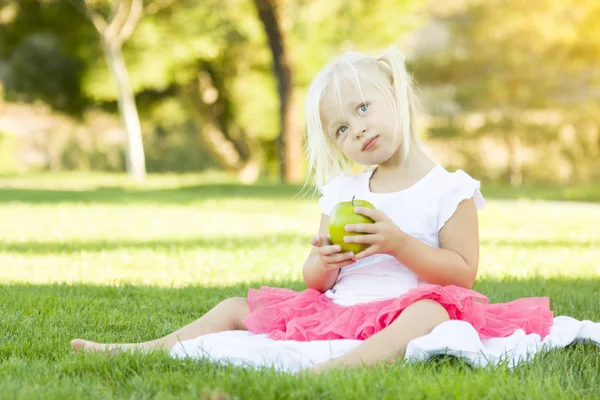 Malá holčička v trávě, jíst zdravé jablko — Stock fotografie