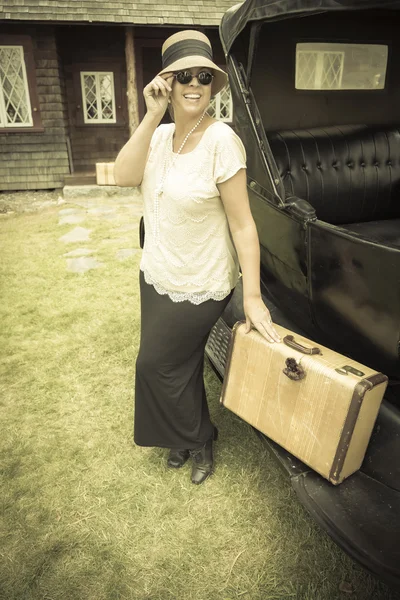 Glada 1920-talet klädda tjej håller resväska bredvid Vintage bil — Stockfoto