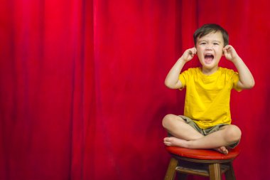 Boy, Fingers In Ears on Stool in Front of Curtain clipart