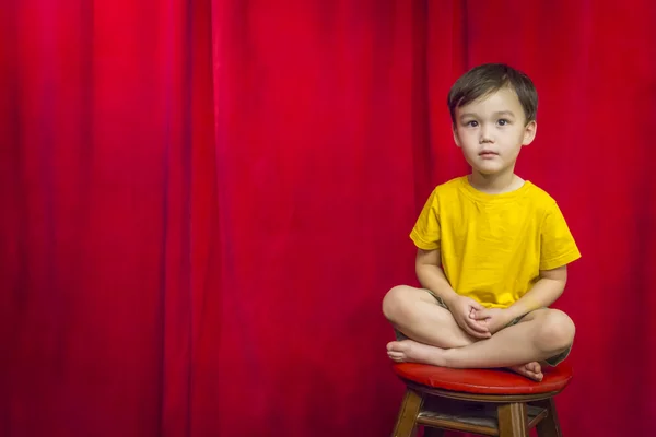 Mixed Race Boy Sitting on Stool in Front of Curtain — Stock Photo, Image