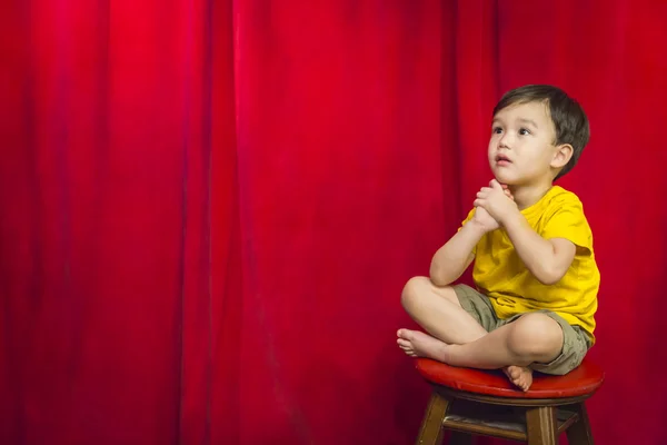 Mixed Race Boy Sitting on Stool in front of Curtain — стоковое фото