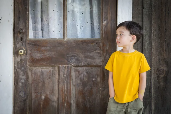 Melancholie gemengd ras jongen staande voor deur — Stockfoto