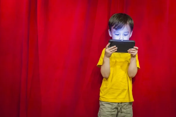 Mixed Race Boy mirando el teléfono celular en frente de la cortina — Foto de Stock