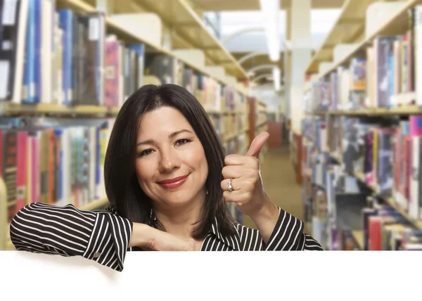Hiszpanin kobieta z kciuki do góry na biały deska w bibliotece — Zdjęcie stockowe