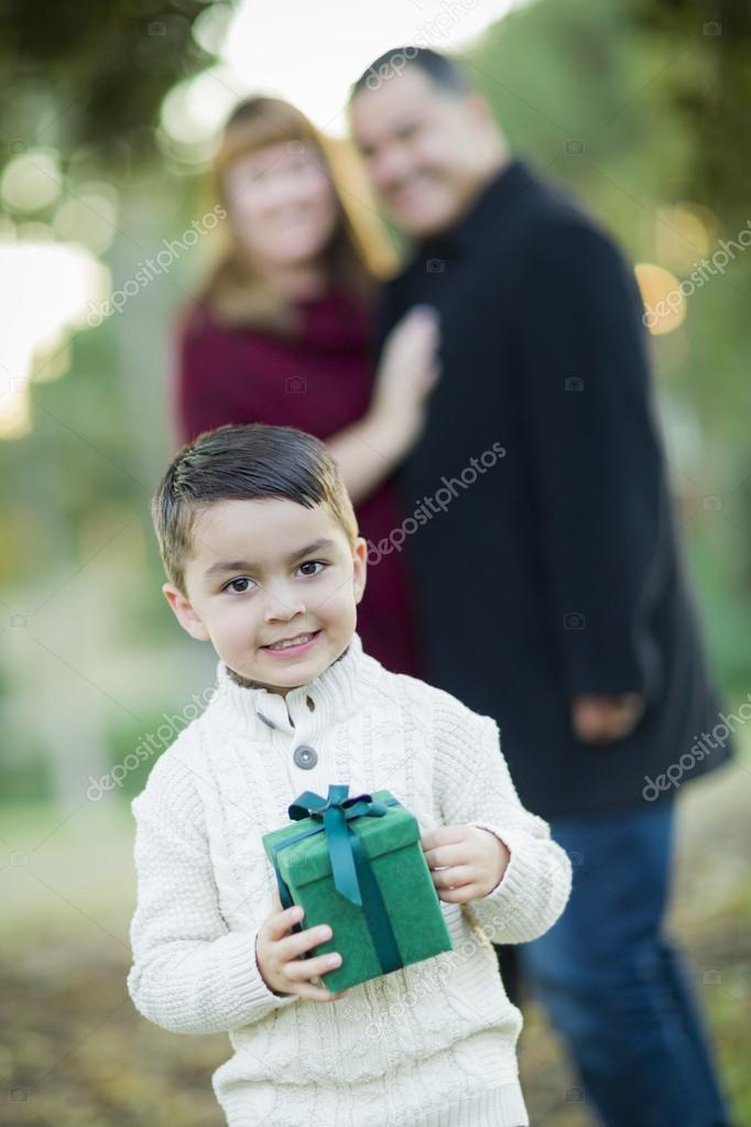 Mixed Race Boy Holding Gift In Front with Parents Behind