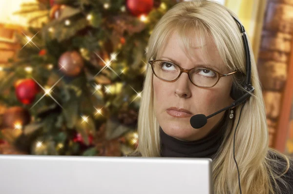 Mulher perturbada com fone de ouvido na frente da árvore de Natal e computador — Fotografia de Stock