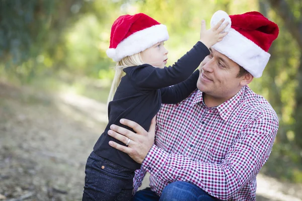 Отец и дочь весело одевают шляпы Санта-Клауса — стоковое фото
