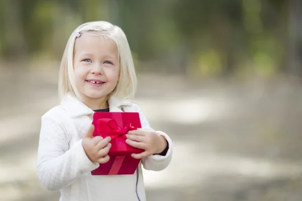 Bébé fille tenant rouge cadeau de Noël en plein air — Photo