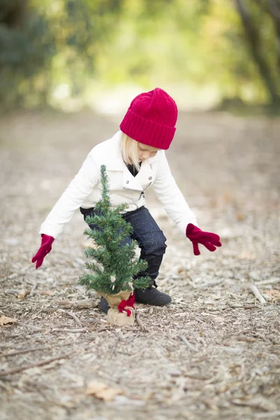 Девочка в красных варежках и маленькой рождественской елке — стоковое фото