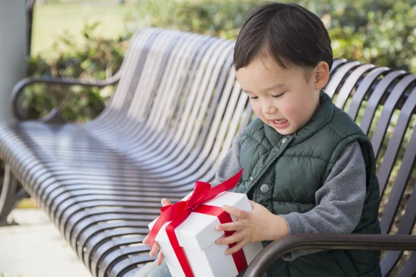 Mixed Race Boy Opening A Christmas Gift Outdoors — Stock Photo, Image