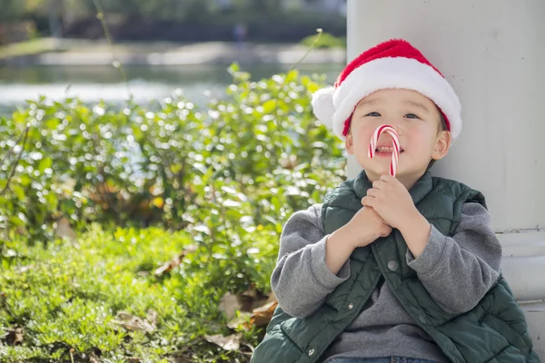 Lindo mezclado raza chico con santa sombrero y caramelo bastón — Foto de Stock