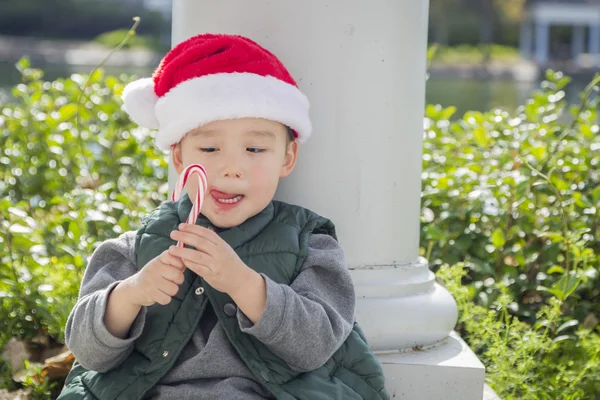 Niedliche gemischte Rasse Junge mit Weihnachtsmütze und Zuckerrohr — Stockfoto