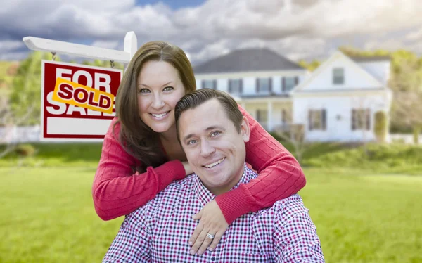 Casal na frente de vendido para venda sinal e casa — Fotografia de Stock