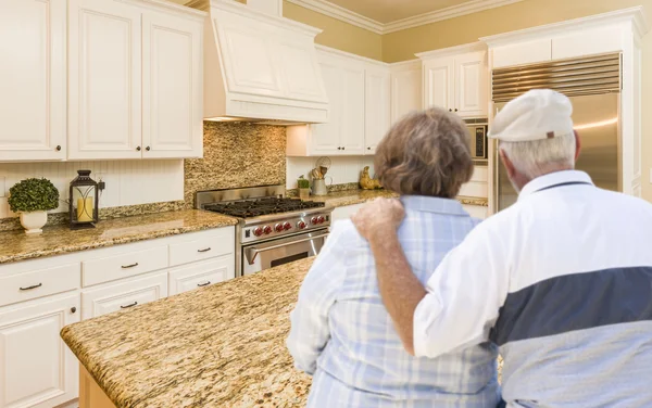 Coppia anziana guardando oltre bella cucina personalizzata — Foto Stock