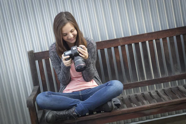 Junge Fotografin blickt auf die Rückseite der Kamera — Stockfoto