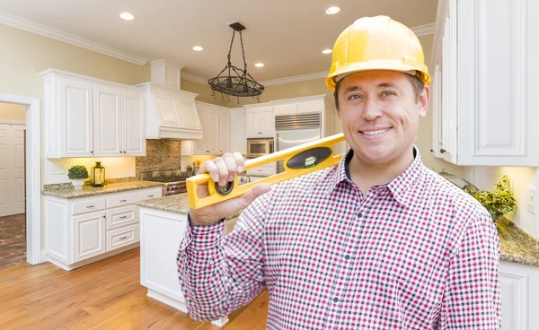 Entrepreneur avec niveau portant le casque dur debout dans la Kitche personnalisée — Photo