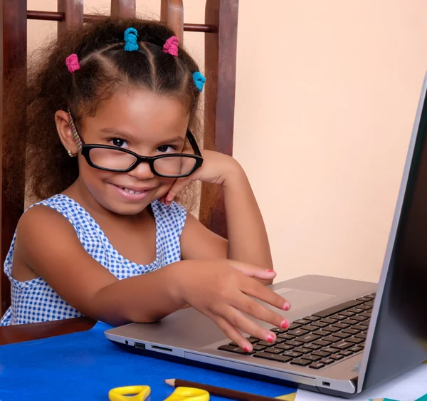 Zabawny wielorasowe mały dziewczyna w okularach i za pomocą laptopa — Zdjęcie stockowe