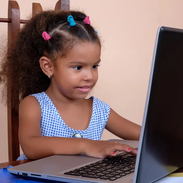 Piccola ragazza multirazziale che lavora su un computer portatile — Foto Stock