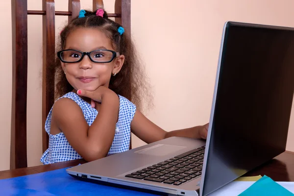 Multiraciale klein meisje dragen van een bril en het gebruik van een laptop comput — Stockfoto