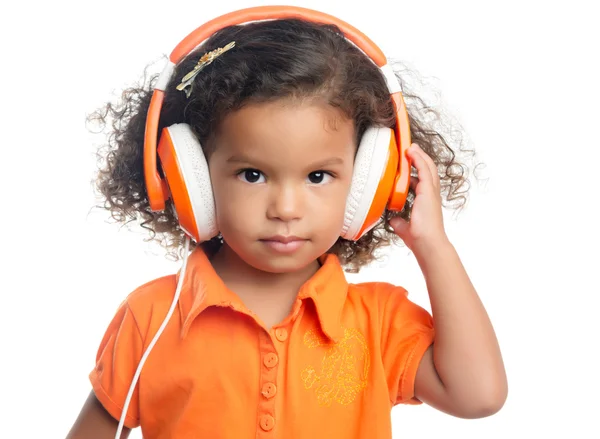 Маленькая девочка с африканской прической наслаждается музыкой на ярко-оранжевых наушниках — стоковое фото