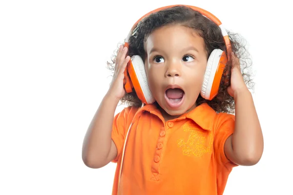 Eccitato bambina con un'acconciatura afro godendo la sua musica su cuffie arancione brillante — Foto Stock