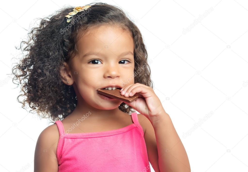 Joyful Little Girl With An Afro Hairstyle Eating A Chocolate Bar