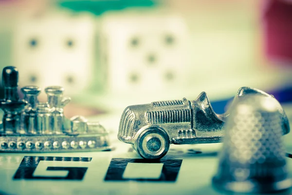 Tokens and dice next to the GO in a Monopoly board — Stock Photo, Image