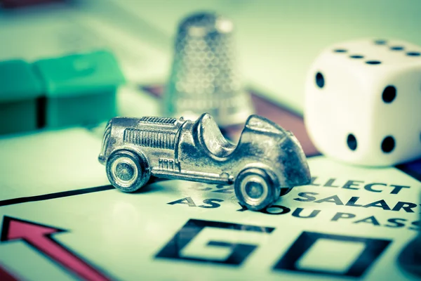 Tokens and dice next to the GO in a Monopoly board — Stock Photo, Image