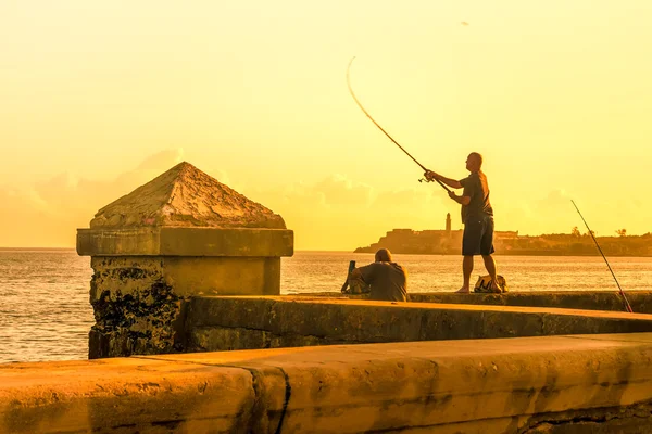 Hombre pescando durante una puesta de sol —  Fotos de Stock