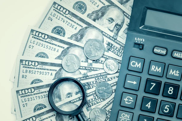 Contas de dólar com uma calculadora e uma lupa — Fotografia de Stock
