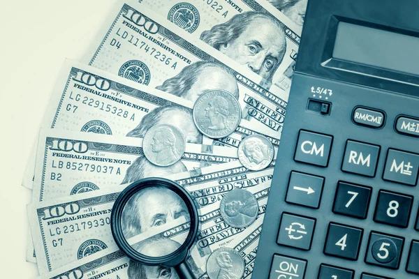 Dollar bills with a calculator and a magnifying glass — Stock Photo, Image