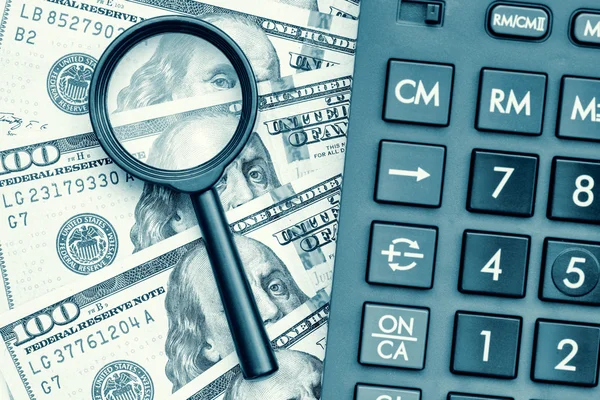 Dollar bills with a calculator and a magnifying glass — Stock Photo, Image