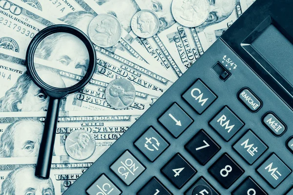 Contas de dólar com uma calculadora e uma lupa — Fotografia de Stock