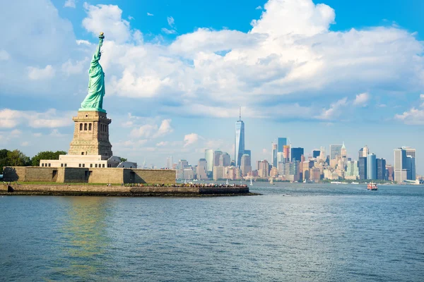 Frihedsgudinden med Manhattans skyline. - Stock-foto