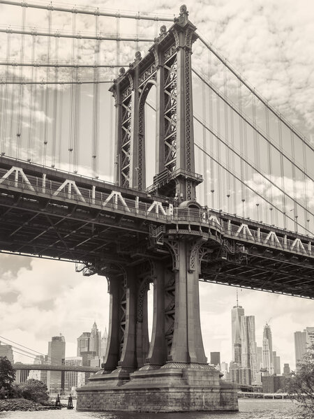 Black and white view of the Manhattan bridge in New York with the city skyline on the background