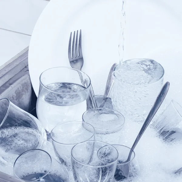 Artículos de vidrio, cubiertos y platos en el fregadero de la cocina — Foto de Stock