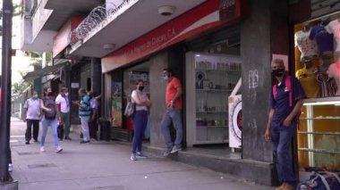 Venezuela 'nın başkenti Chacaito, Caracas' taki Plaza Brion 'da 19 Aralık 2020' de meydana gelen COVID-19 virüsü nedeniyle çoğu koruyucu maskeli, kimliği belirsiz kişiler