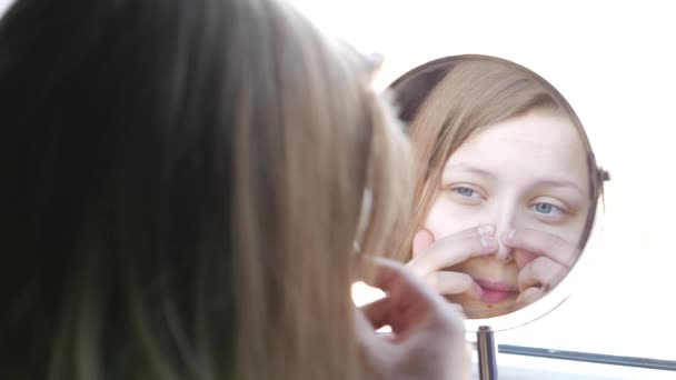 Modèle de beauté adolescente regardant dans le miroir et vérifier sa peau, l'application de maquillage. 4K — Video