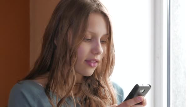 Девушка-подросток со смартфоном, болтает и разговаривает. 4K UHD . — стоковое видео