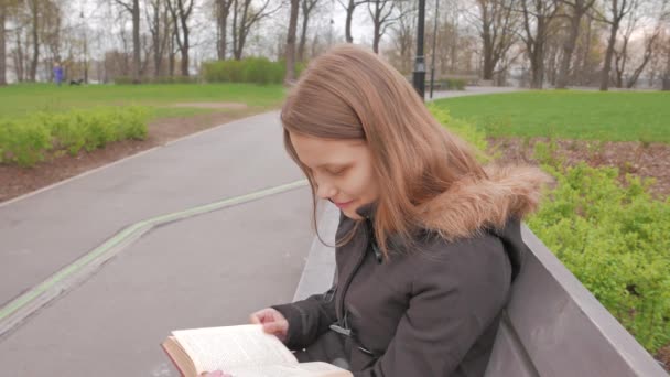 Tiener meisje het lezen van een boek in een park. 4k Uhd — Stockvideo