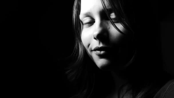 Gros plan portrait noir et blanc contrasté d'une jeune adolescente souriant à la caméra. 4K UHD .