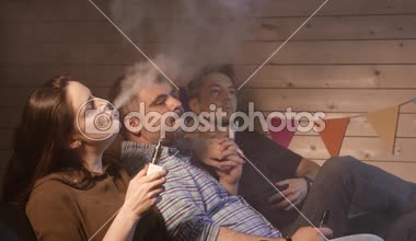 Bir grup insanlar vaping, teneffüs edilmesi ve büyük bulutlar duman exhaling ve birlikte eğlenmek. İyi arkadaş şirket. 4k Uhd.
