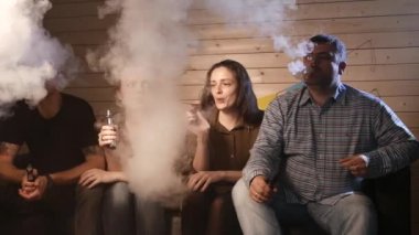 Bir grup insanlar vaping, teneffüs edilmesi ve büyük bulutlar duman exhaling ve birlikte eğlenmek. İyi arkadaş şirket. 4k Uhd.