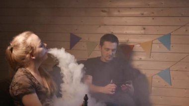 Bir grup insanlar vaping, teneffüs edilmesi ve büyük bulutlar duman exhaling ve birlikte eğlenmek. İyi arkadaş şirket. 4k Uhd.