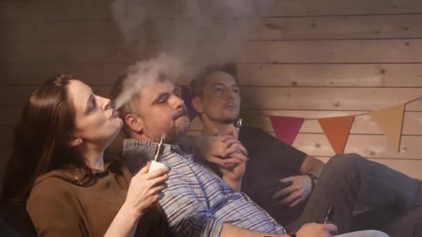 Μια ομάδα ανθρώπων vaping, εισπνοή και εκπνέετε μεγάλα σύννεφα καπνού και να διασκεδάσουμε μαζί. Εταιρεία από τους καλούς φίλους. 4k Uhd. — Αρχείο Βίντεο