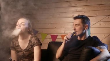 Bir grup insanlar vaping, teneffüs edilmesi ve büyük bulutlar duman exhaling ve birlikte eğlenmek. İyi arkadaş şirket. 4k Uhd.