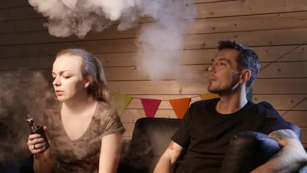 A group of people vaping, inhaling and exhaling large clouds of smoke and having fun together.  Company of good friends. 4K UHD. — Stock Video