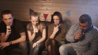 Bir grup insanlar vaping, teneffüs edilmesi ve büyük bulutlar duman exhaling ve birlikte eğlenmek. İyi arkadaş şirket. 4k Uhd.