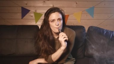Bir kanepe ve vaping e-sigara üzerinde oturan bir kız. 4k Uhd